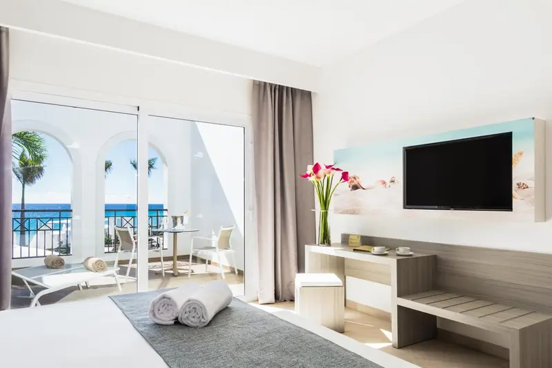 Chambre lumineuse avec un balcon donnant sur la mer.