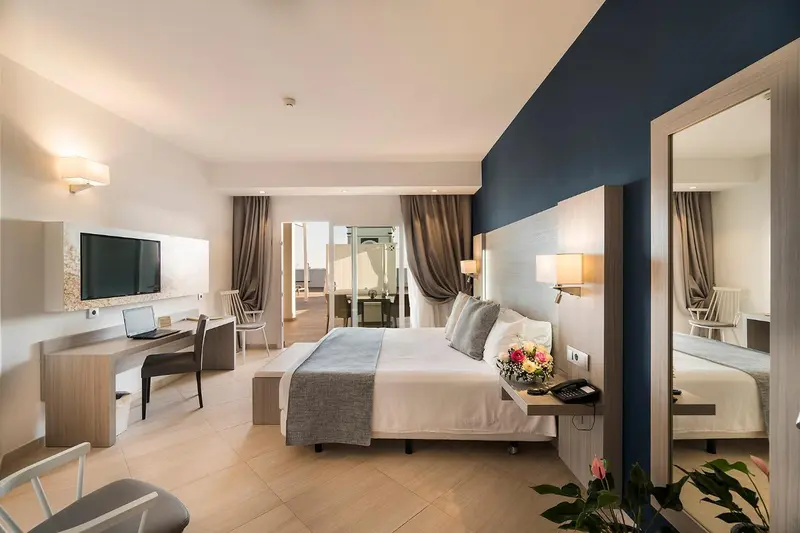 Une chambre lumineuse avec un grand lit et un espace bureau.