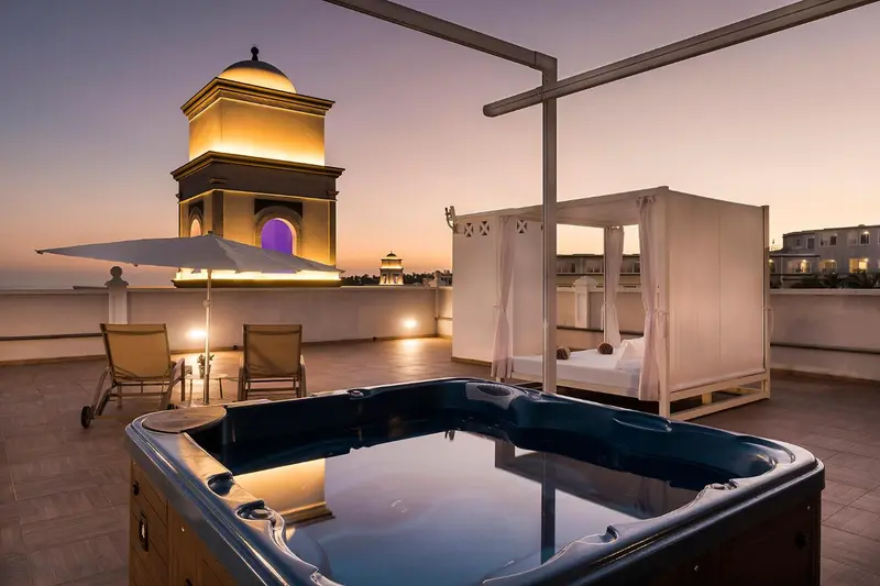 Terrasse avec jacuzzi et mobilier de détente au coucher du soleil.