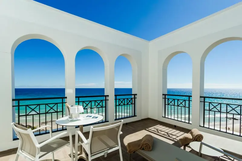 Terrasse avec table et chaises donnant sur la mer.