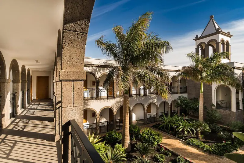 Cour intérieure d'un bâtiment avec des arcades et une végétation luxuriante.