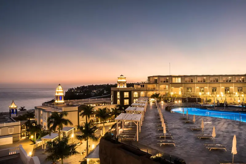 Vue nocturne d'un complexe hôtelier illuminé au bord de la mer.