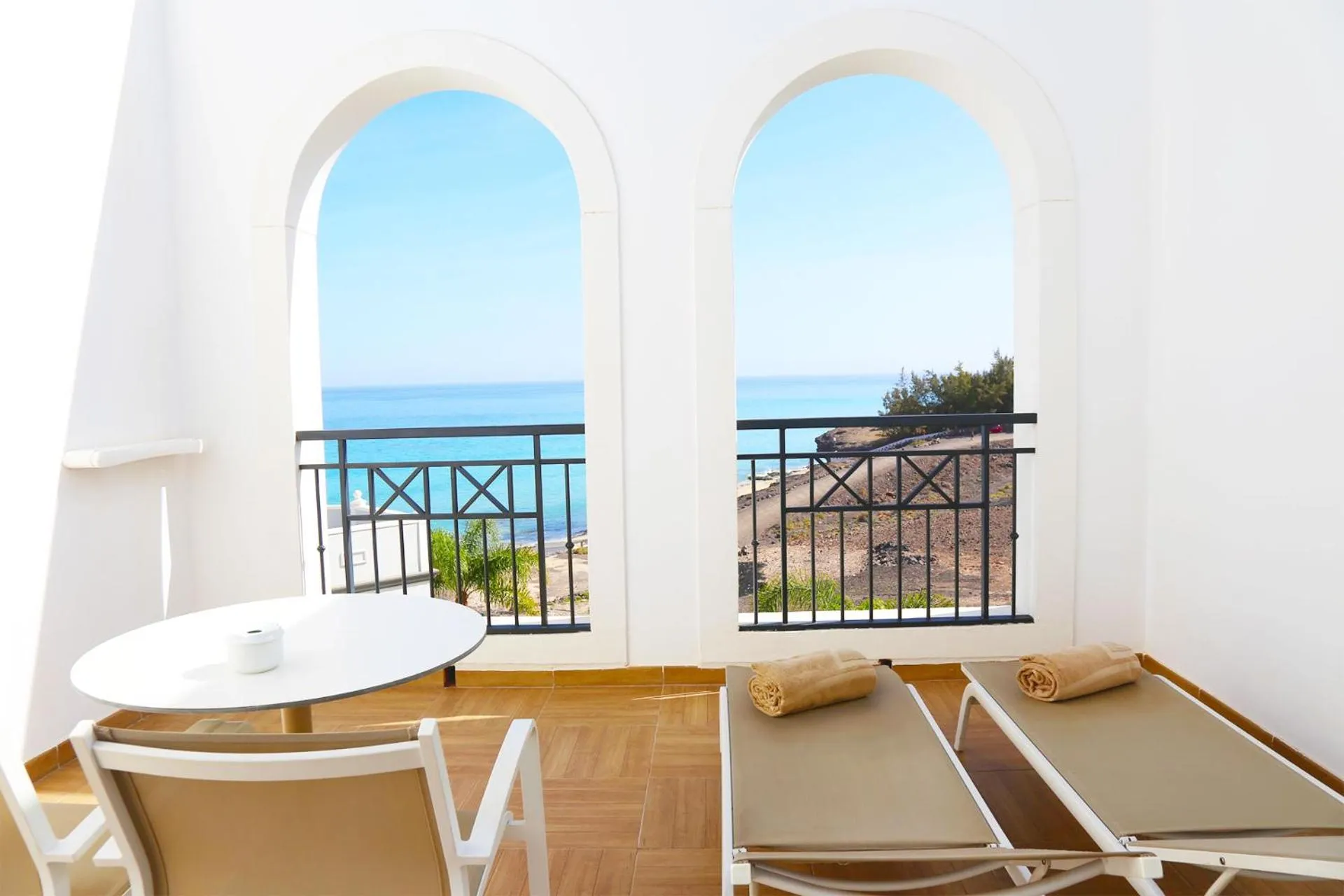 Terrasse avec table et chaises longues donnant sur la mer.