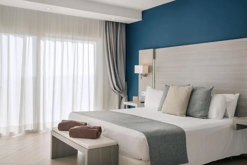 Une chambre lumineuse avec un grand lit et des rideaux blancs.