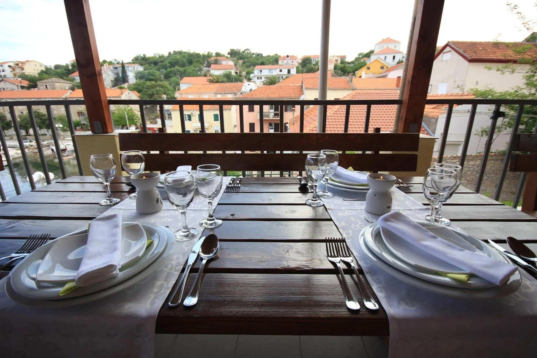 Une table dressée pour un repas en extérieur avec vue sur la ville et le port.