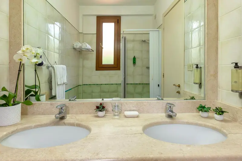 Salle de bain lumineuse avec deux vasques et douche à l'italienne.