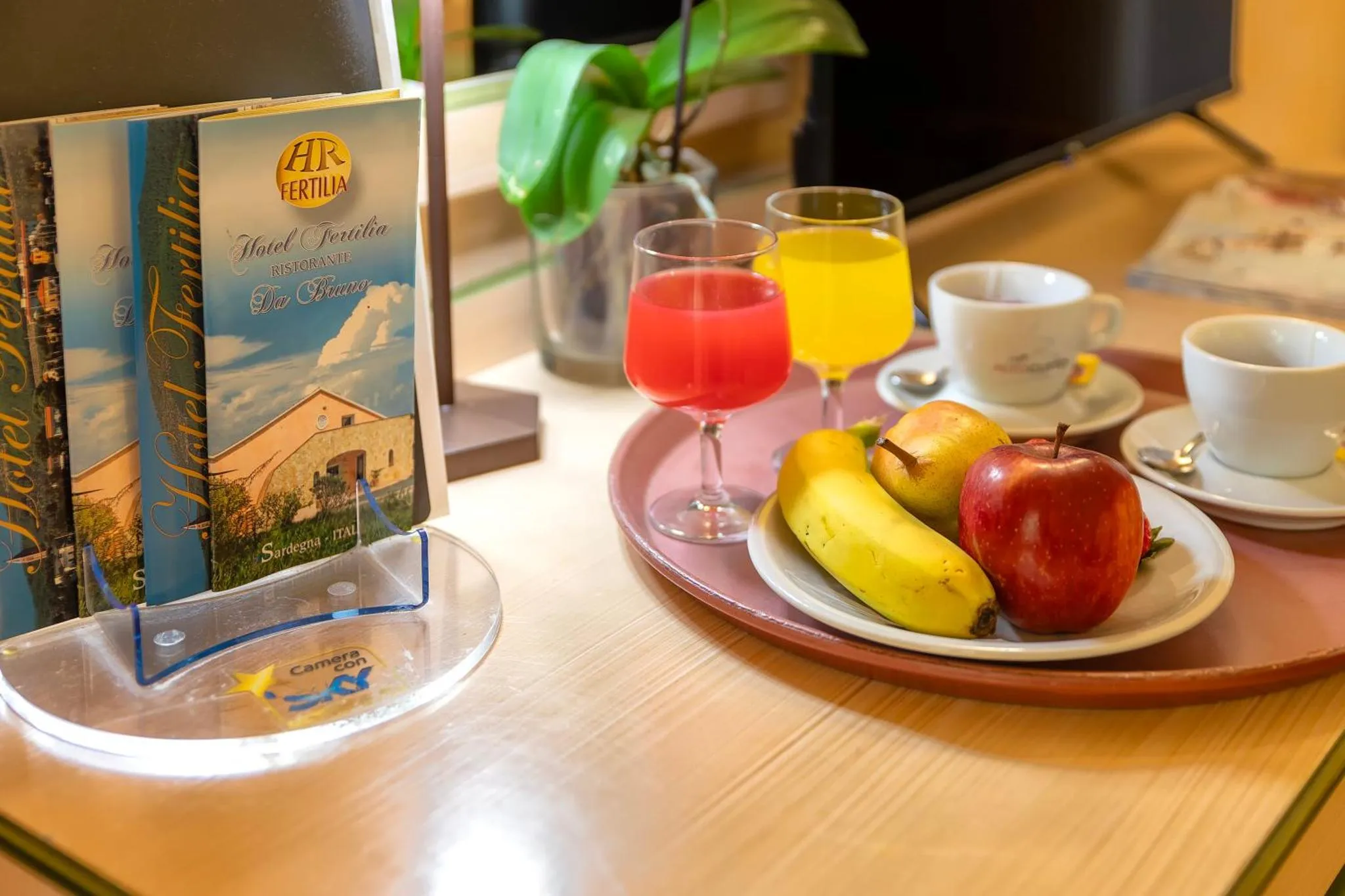 Un plateau de petit-déjeuner avec des jus de fruits, une banane et une pomme est présenté sur une table.
