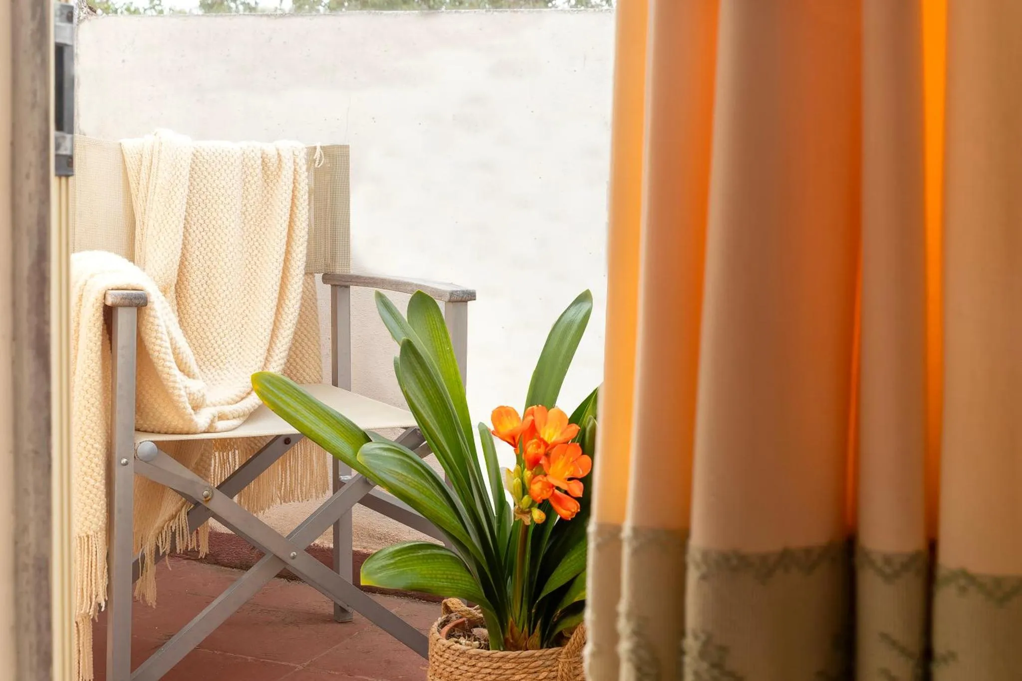 Un fauteuil en osier avec une couverture posée sur une terrasse.