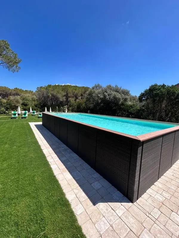 Une piscine rectangulaire bordée d'une pelouse verdoyante sous un ciel bleu.