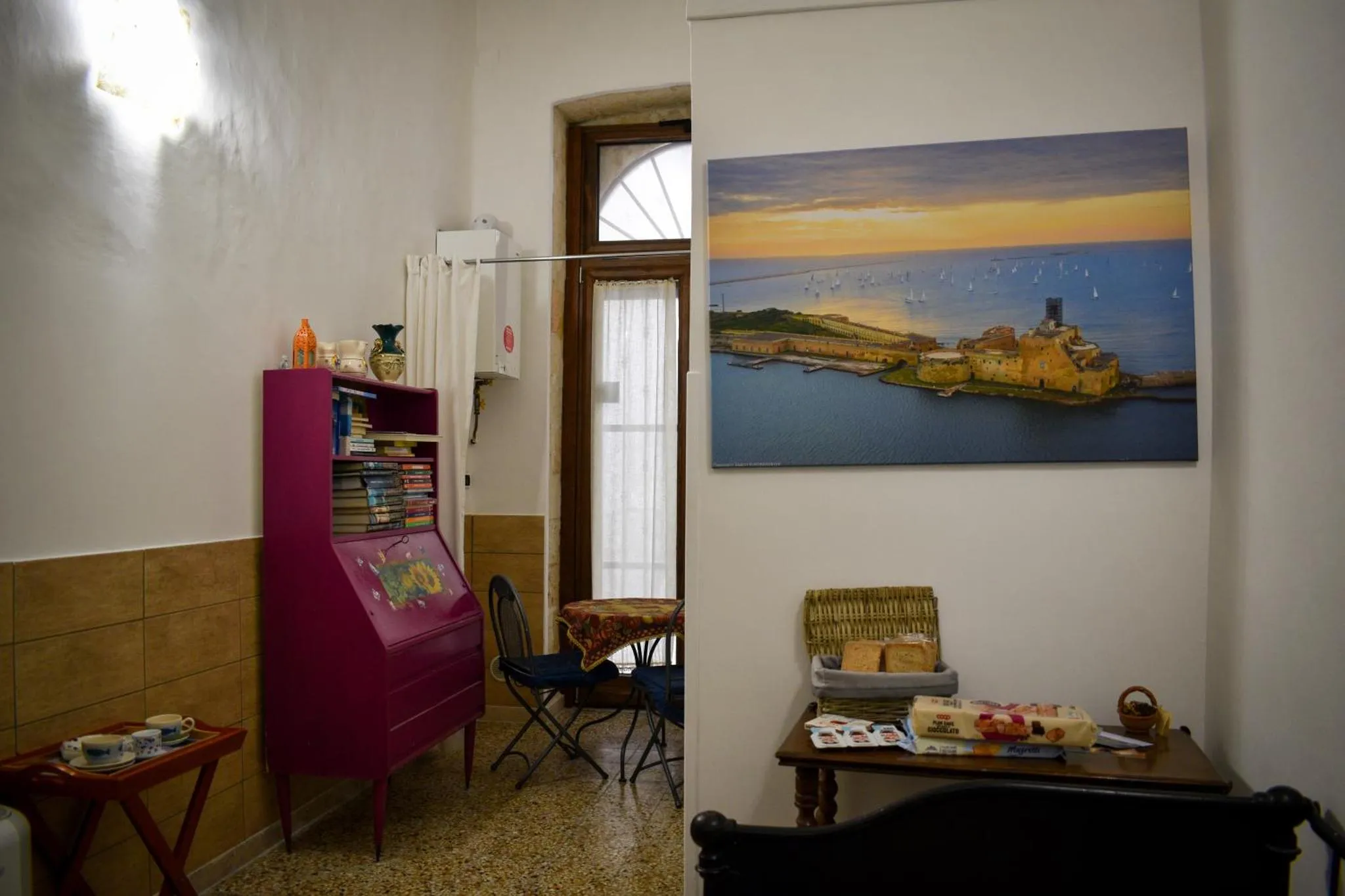 Une pièce lumineuse avec un bureau rose et une vue sur la mer à travers une fenêtre.