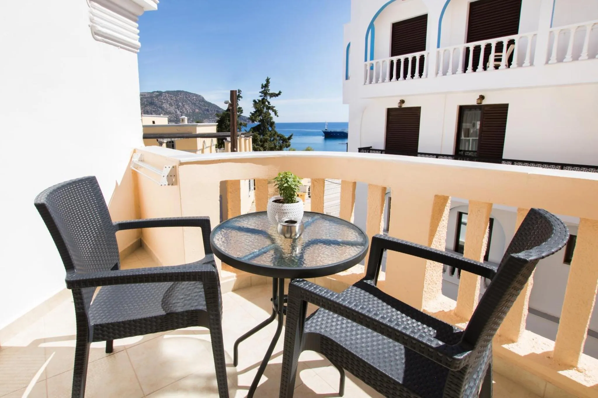 Terrasse avec table et chaises en osier noir donnant sur la mer.