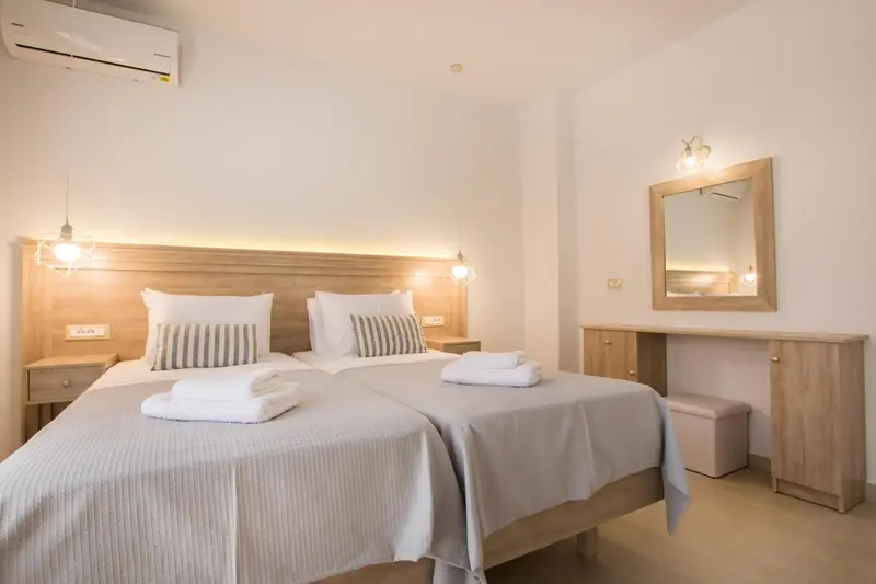 Une chambre lumineuse avec deux lits simples et un espace coiffeuse.