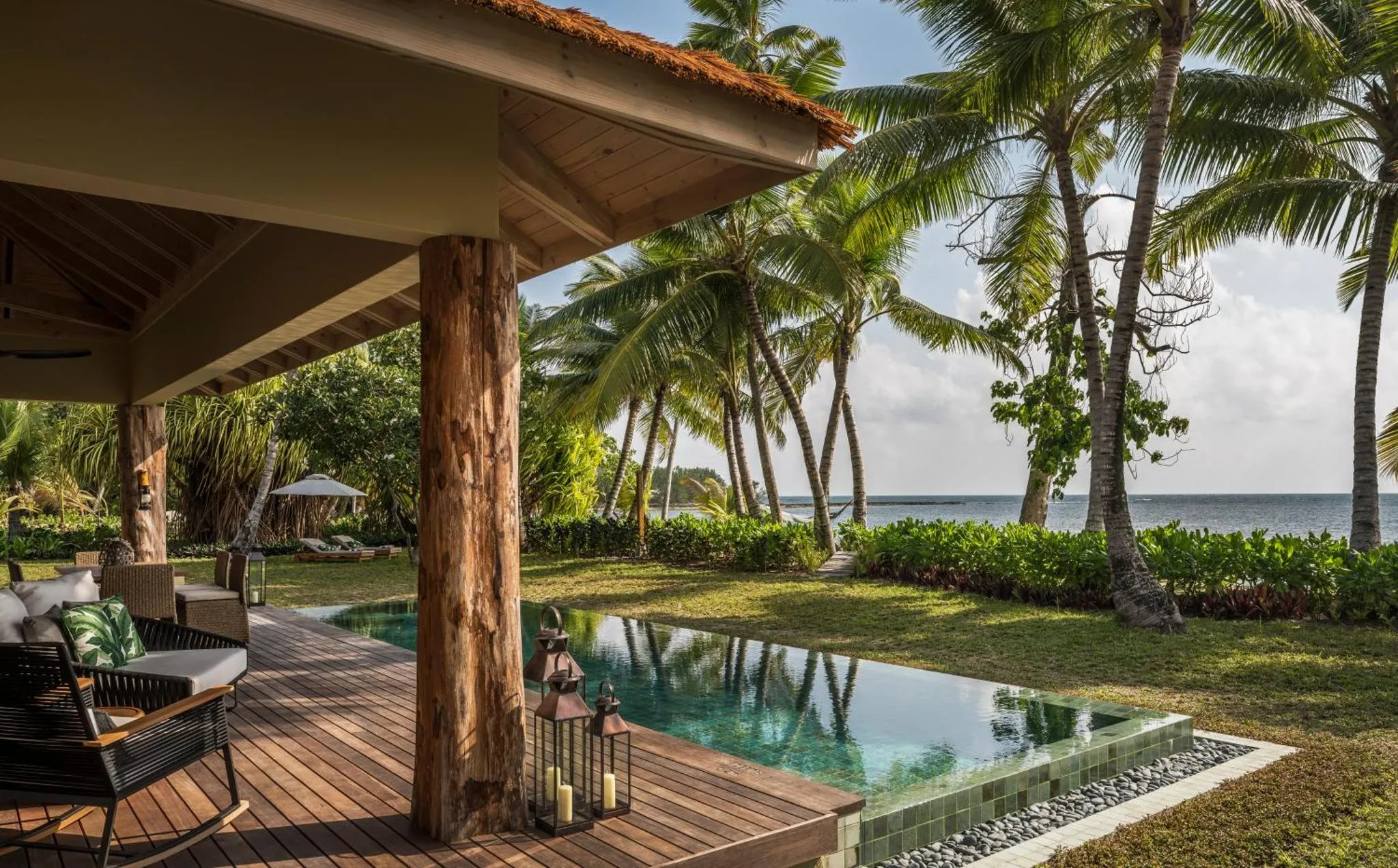 Terrasse en bois avec salon et petite piscine donnant sur la mer.