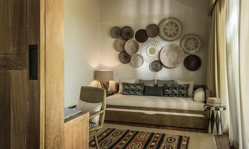 Une chambre décorée de plateaux tressés au mur et d'un tapis ethnique.