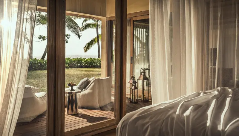 Une chambre lumineuse s'ouvre sur une terrasse avec vue sur la végétation tropicale.
