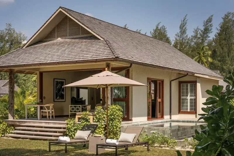 Bâtiment à toit en pente avec terrasse et mobilier de jardin.