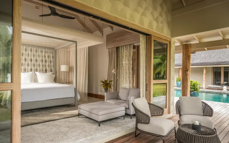 Une chambre lumineuse s'ouvre sur une terrasse avec salon et piscine.