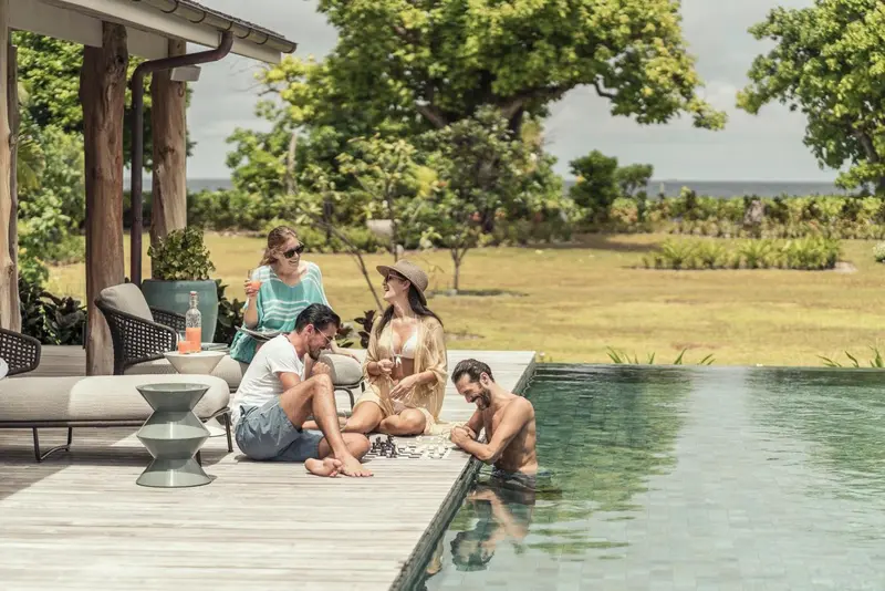 Des personnes discutent et se détendent au bord d'une piscine à débordement.