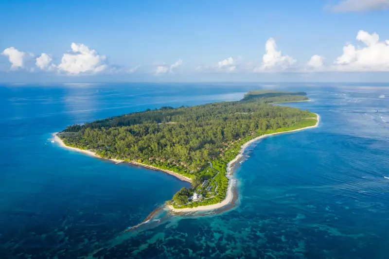 Vue aérienne d'une île tropicale bordée de plages et de végétation luxuriante.