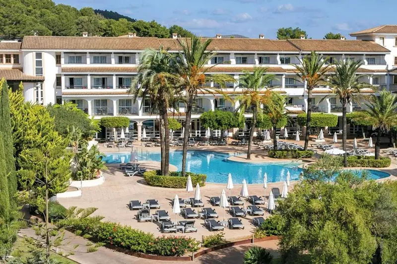 Vue aérienne d'un complexe hôtelier avec piscine et palmiers.