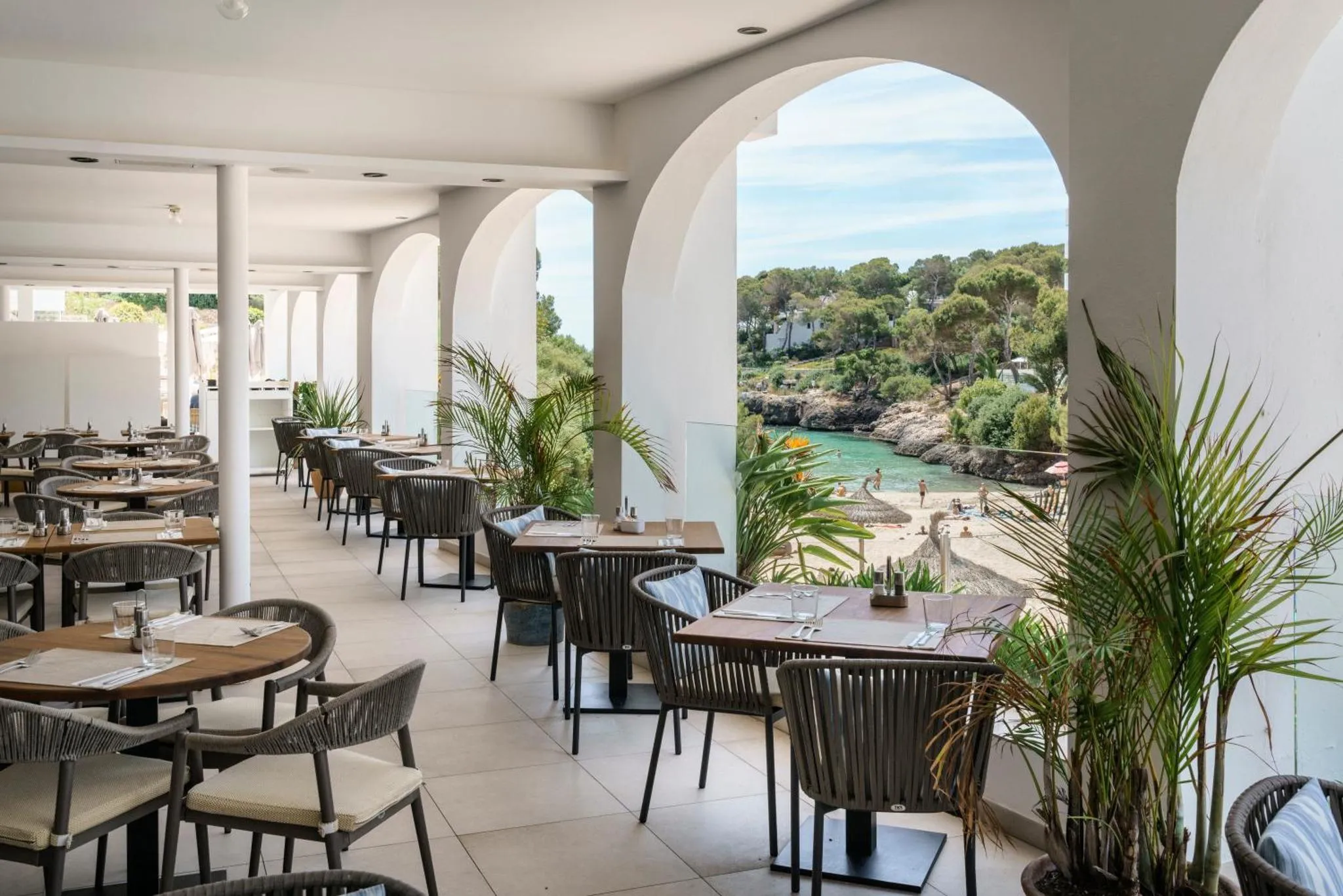 Une salle à manger lumineuse s'ouvre sur une vue sur la mer et une petite crique.