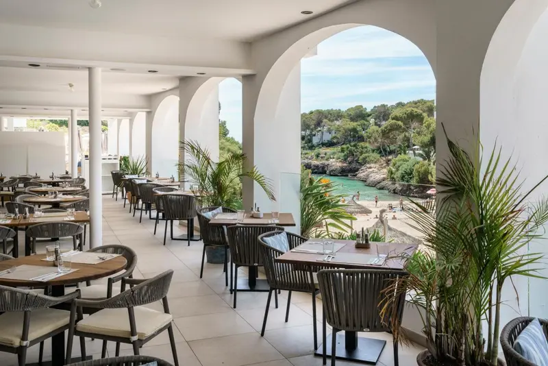 Une salle à manger lumineuse s'ouvre sur une vue sur la mer et une petite crique.