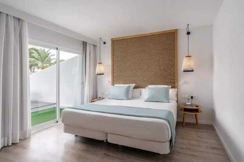 Une chambre lumineuse avec un grand lit et un accès à une terrasse.