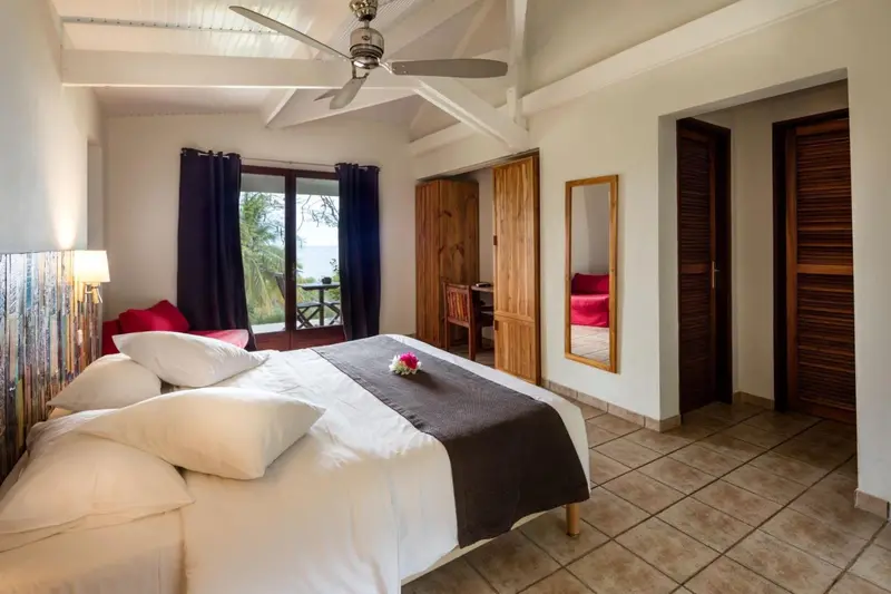 Une chambre lumineuse avec un lit recouvert d'une courtepointe et un accès à un balcon.