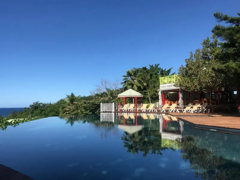Une piscine à débordement surplombe un paysage verdoyant et la mer.