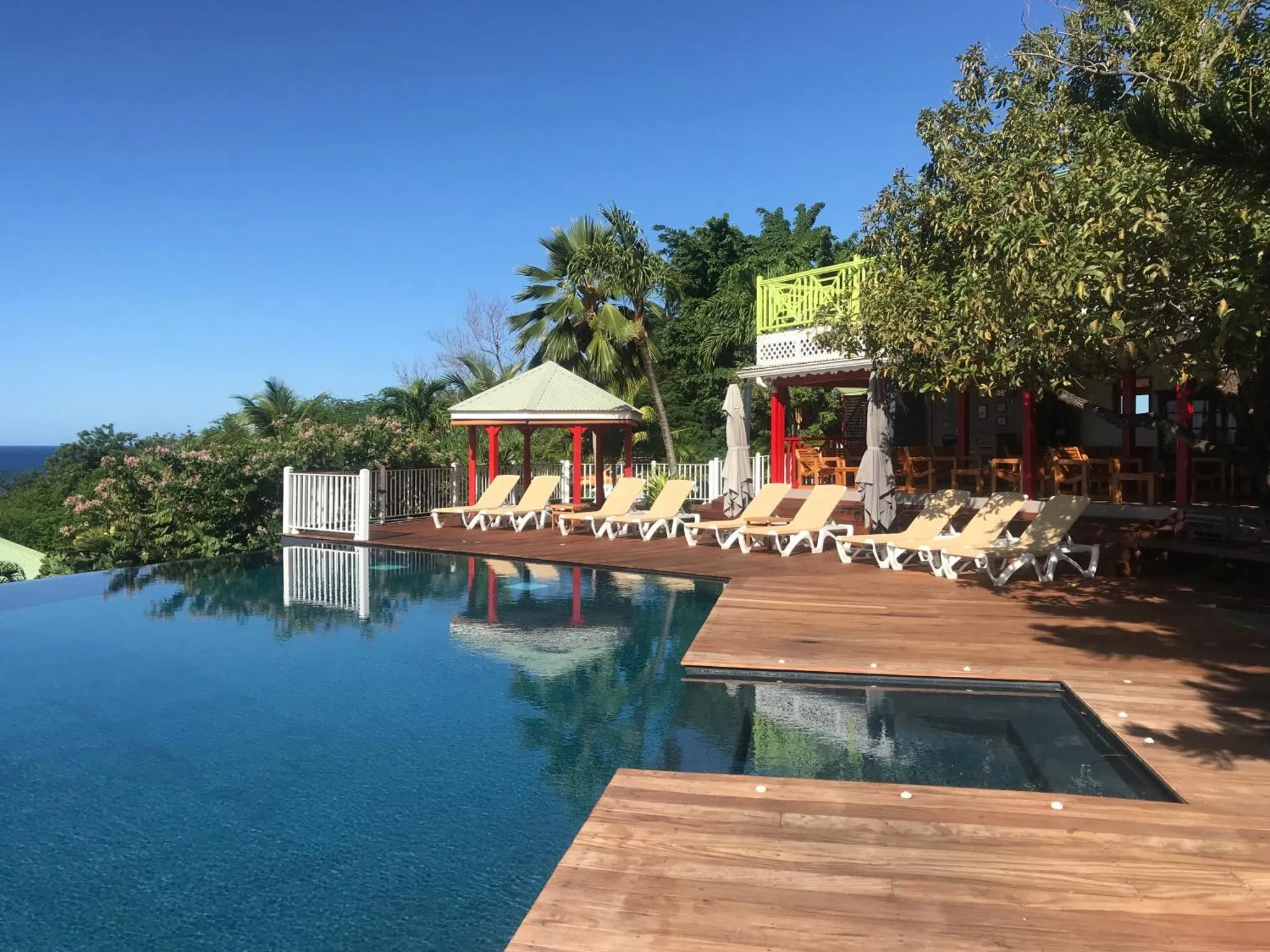 Terrasse avec transats et piscine à débordement offrant une vue sur la mer.
