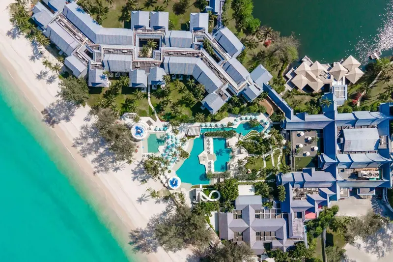 Vue aérienne d'un complexe hôtelier bordant une plage de sable blanc et une mer turquoise.