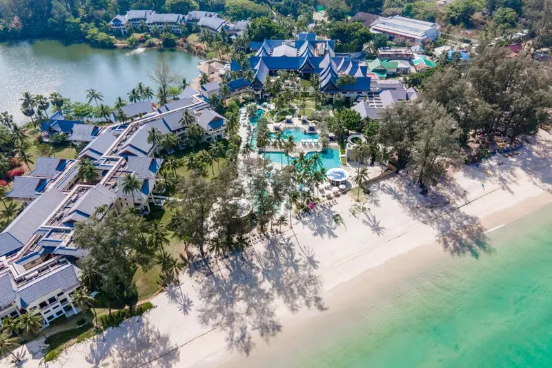 Vue aérienne d'un complexe hôtelier bordant une plage de sable blanc et une eau turquoise.