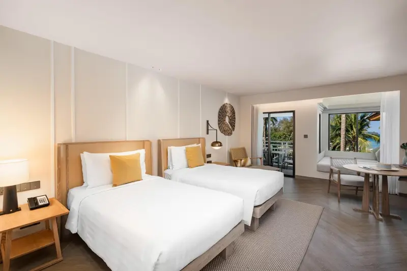 Chambre lumineuse avec deux lits simples et un espace détente.