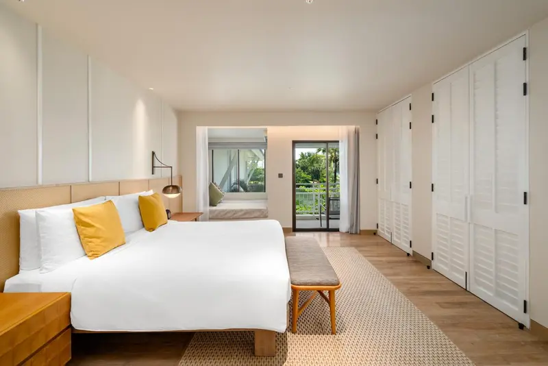 Une chambre lumineuse avec un grand lit et un accès à un balcon.