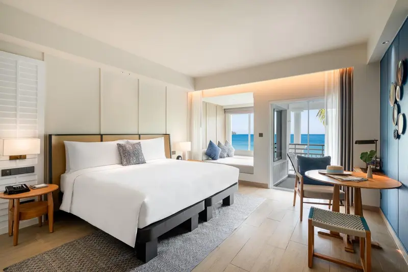 Une chambre lumineuse avec un grand lit et un coin salon donnant sur l'océan.