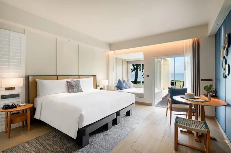 Une chambre lumineuse avec un grand lit et un coin salon donnant sur une vue sur la mer.