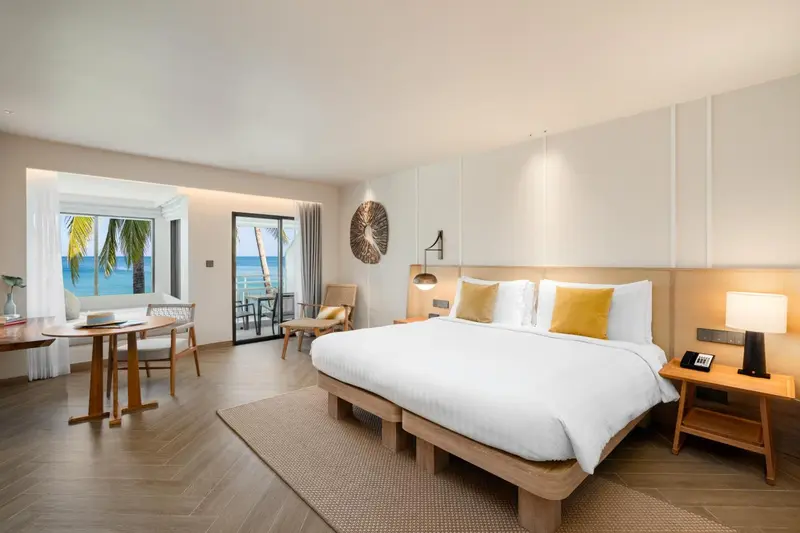Chambre lumineuse avec un grand lit et vue sur la mer.