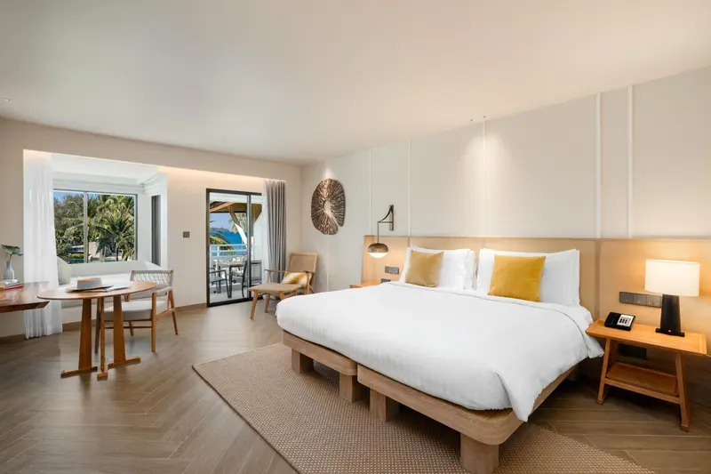 Chambre lumineuse avec un grand lit et un espace repas.