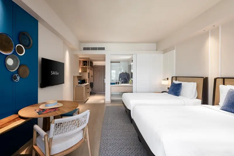 Une chambre lumineuse avec deux lits simples et un coin repas.