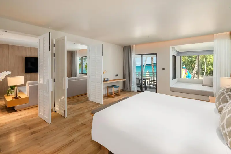 Une chambre lumineuse avec un lit king-size et un coin salon donnant sur une vue sur la mer.