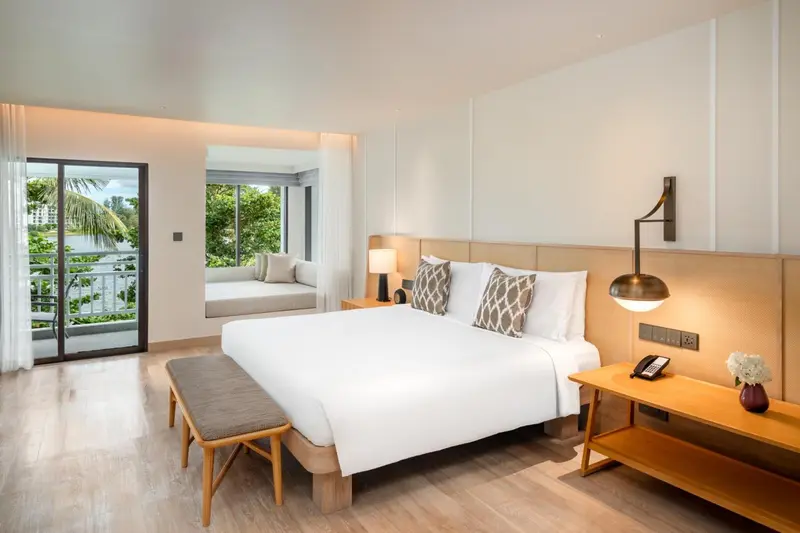 Une chambre lumineuse avec un grand lit et un accès à un balcon.