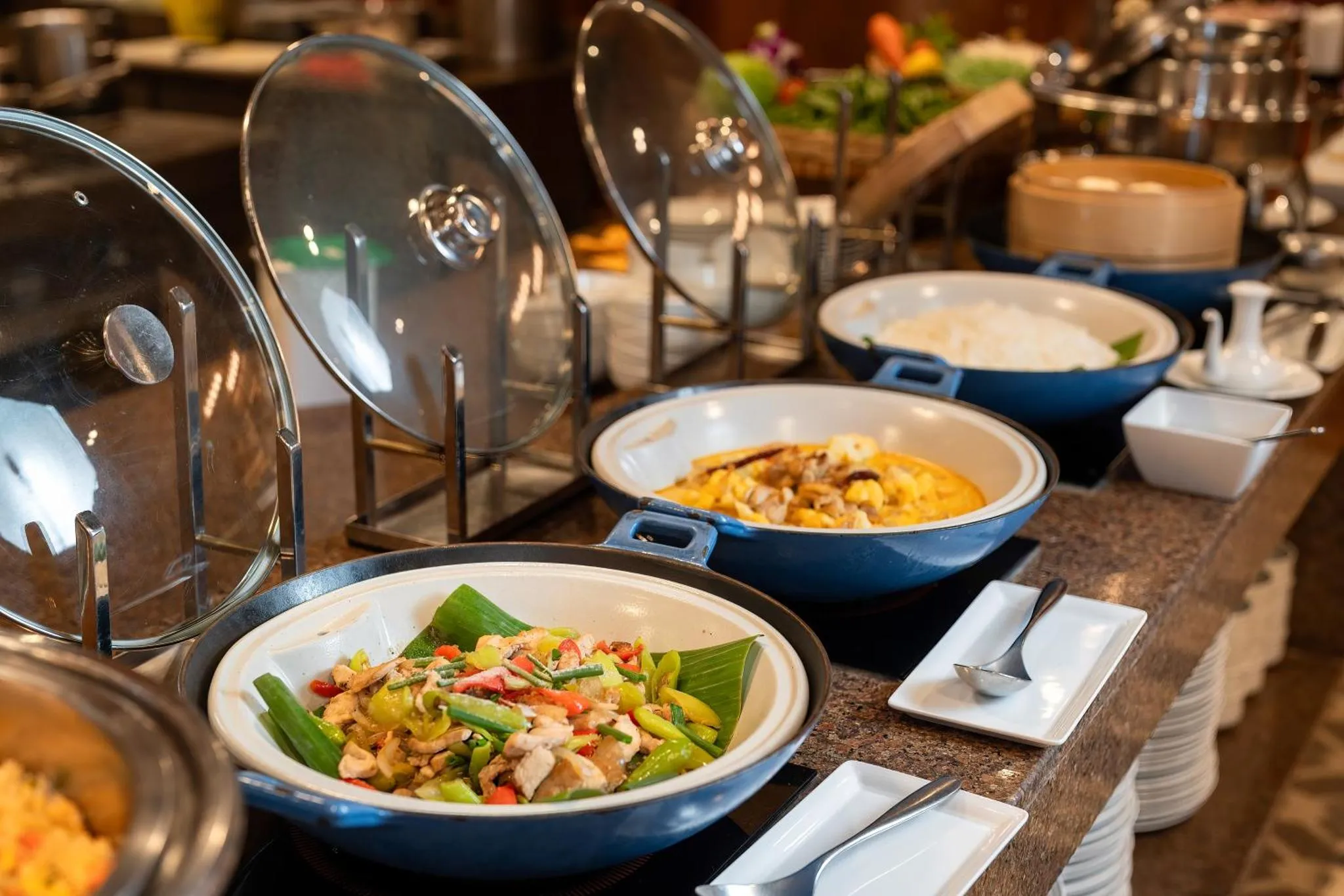 Un buffet propose une variété de plats chauds et de salades colorées.