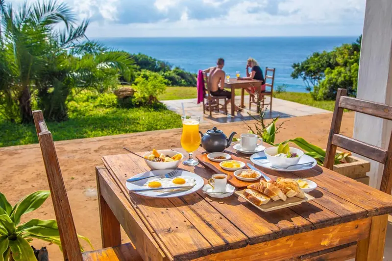 Une table de petit-déjeuner est mise en scène sur une terrasse avec vue sur la mer.