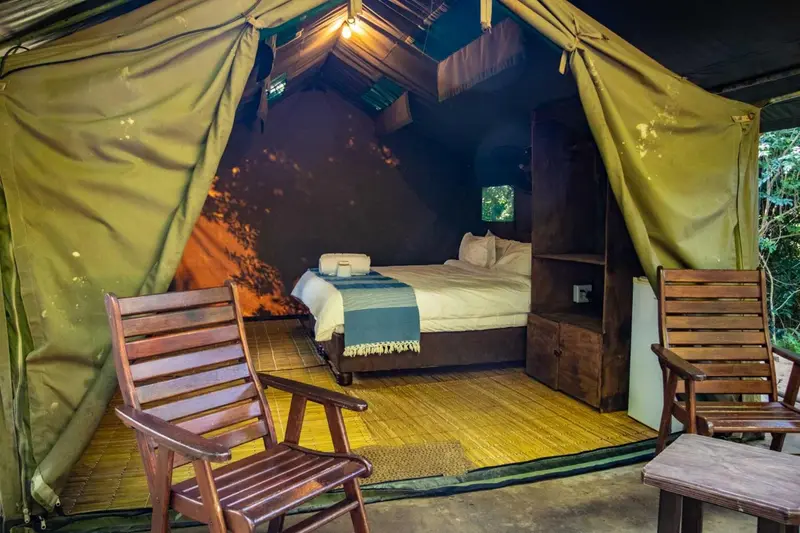 Une tente ouverte sur une chambre avec un lit et des tables de chevet.