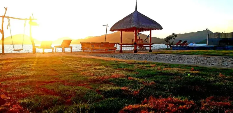 Un espace de détente en bord de mer avec des chaises longues et un gazebo au coucher du soleil.