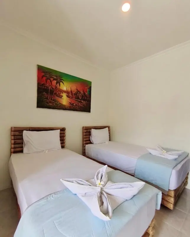 Une chambre lumineuse avec deux lits simples et une décoration murale tropicale.
