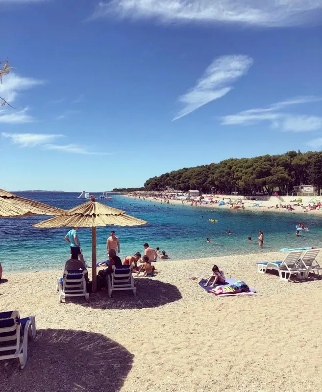 Plage de sable avec transats et parasols sous un ciel bleu.