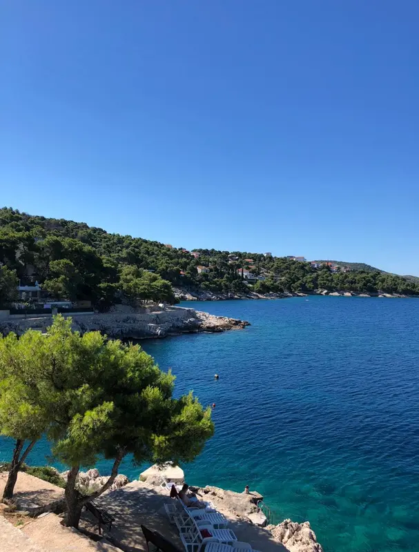 Vue sur une crique rocheuse et une mer bleue sous un ciel clair.