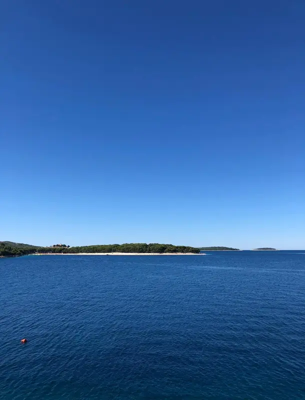 Vue sur une côte rocheuse et une plage de sable fin sous un ciel bleu dégagé.