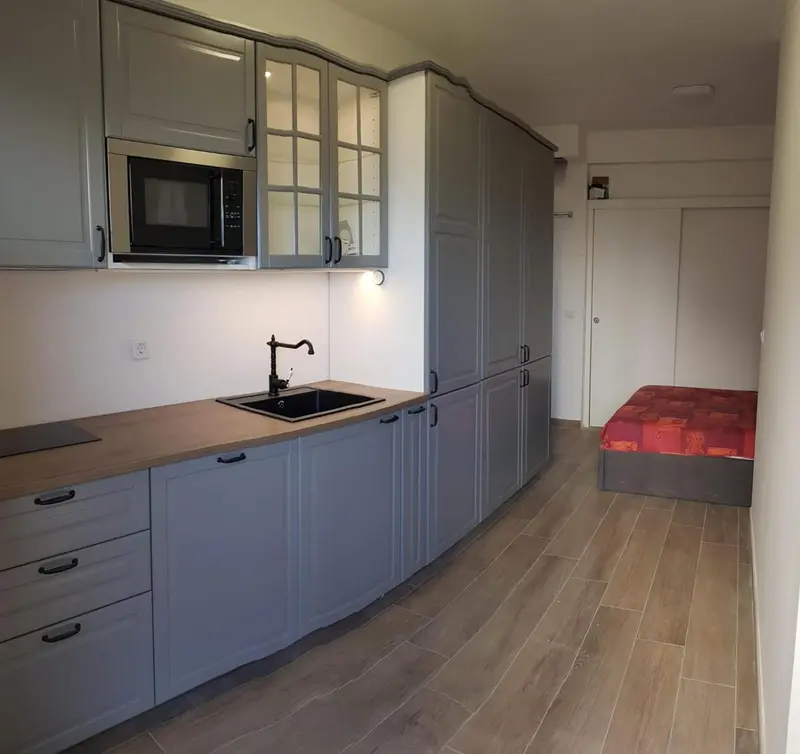Une cuisine moderne avec des meubles gris et un plan de travail en bois.